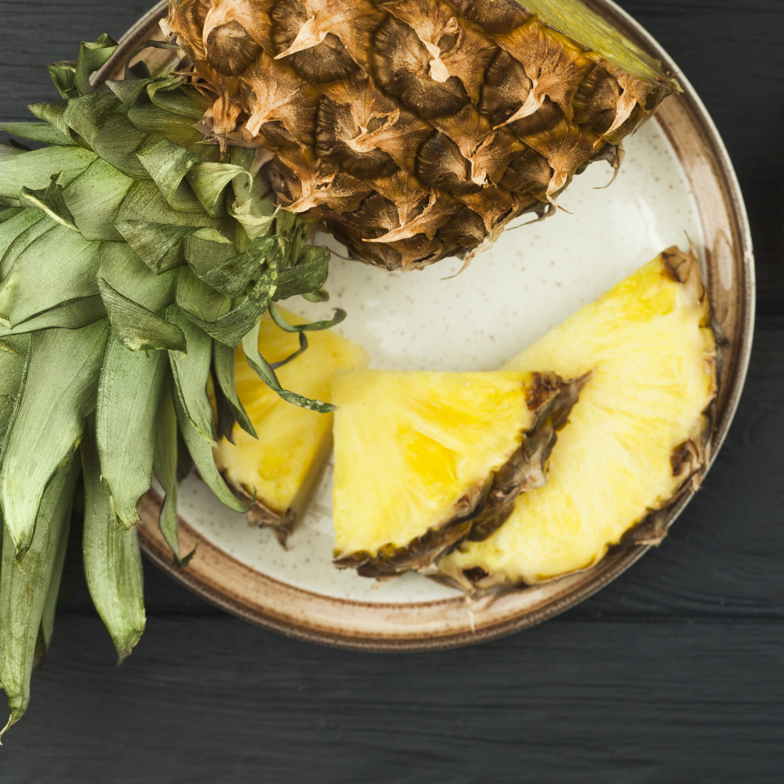 slices pineapple with green leaves plate